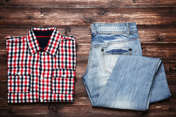Folded shirt and jeans on brown wooden table