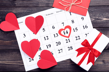 Valentine day calendar with paper hearts and gift boxes on wooden table