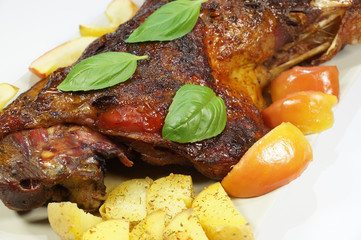 Tastefully served roasted turkey thigh with apples, potatoes  and basil.