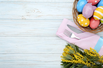 Kitchen cutlery with easter eggs and mimosa flowers on wooden table