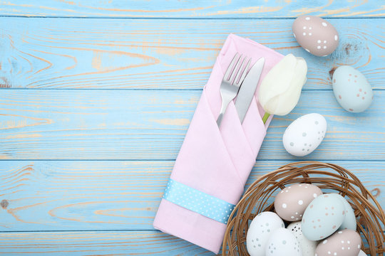 Kitchen cutlery with easter eggs and tulip flower on wooden table