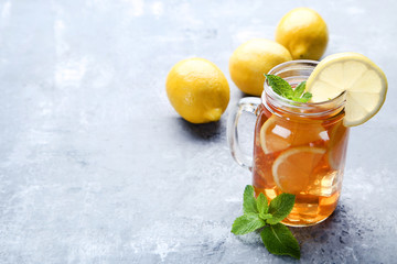 Ice tea in glass jar with lemon and mint leafs on wooden table