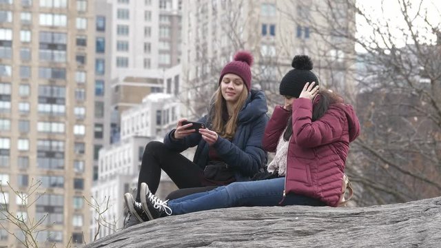 Two girls sit on a rock in Central Park New York