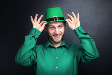 St. Patrick's Day. Young man wearing green hat on black background