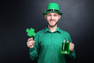 St. Patrick's Day. Young man wearing green hat with glass of beer and paper clover