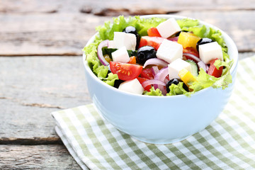 Vegetable salad in bowl with napkin on wooden table