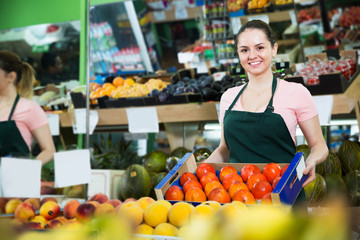Obraz premium Grocery worker offering persimmons