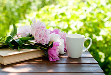  book, flowers and a cup of tea on a table in a spring garden, spring or summer card or calendar