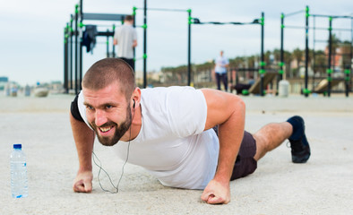Fototapeta premium man performs push-ups on sportsground
