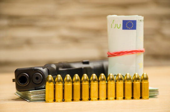 The pistol with bullets stays behind money with bllured wall backspace