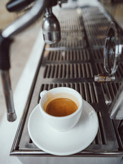 close-up view of glass cup with cappuccino and coffee machine