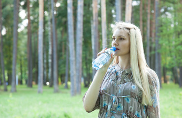 Charming young woman drinking water outdoors