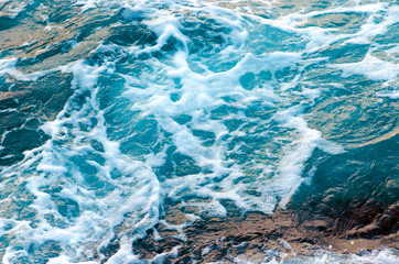 Obraz premium Foamy water waves at the ocean, view from above. Top view sea texture. Photo with motion blur.
