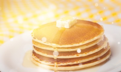 Stack of Small pancakes in syrup on background