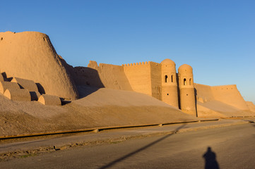 Shadow of a photographer in front of Ichan Kala city wall and south gate during sunset - Khiva, Uzbekistan