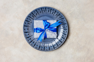 Blue plate with gift box with blue bow at white background