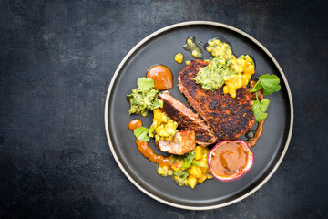 Traditional exotically blackened Cajun style tuna fish fillet with mango avocado salad, chimichurri...