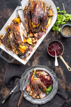 Traditional barbecue pheasant with vegetable and cranberry sauce as top view in a stewpot and on a plate