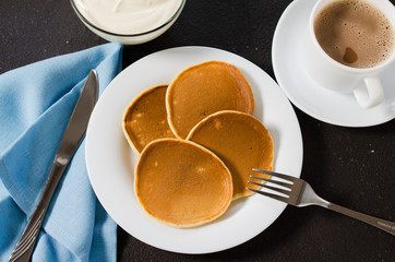 Homemade classic american pancakes and a cup of coffee with milk.