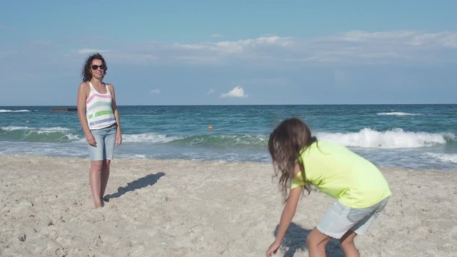 Child playing in flying disc with mother. Mother and daughter play a flying disc on the beach.