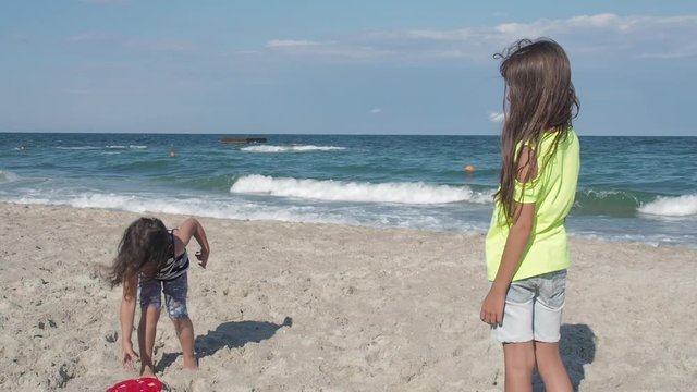 Children playing with flying disc. Little girls play friskis on the beach.