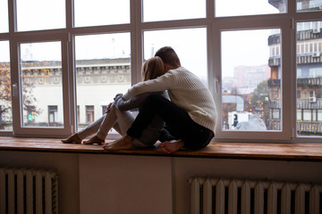 Happy young couple sits near window in the room