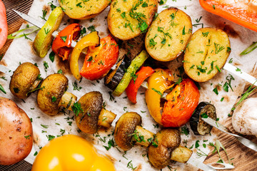 Variety of BBQ grilled vegetables lunch. skewers with  potatoes, tomatoes, mushrooms, eggplants, zucchinis  on  wood background.