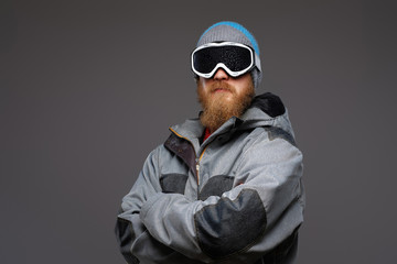 Portrait of a confident snowboarder wearing full protective equipment, posing with his arms crossed