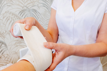 A woman doctor makes a bandage elastic bandage on the hand of a woman with problems on the wrist when the ligament is damaged, as a result of the struggle