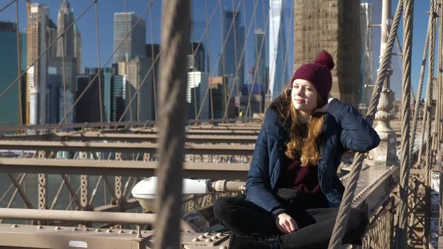 Beautiful girl on Brooklyn Bridge enjoys a sunny day while relaxing
