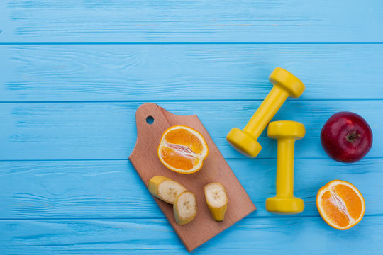 Fruits and dumbbells on color wooden background. Weight loss concept. Your healthy dicision. Get healthy today.