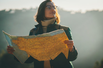 Happy smiling traveller girl holding big map and preparing a route for her trip around the...