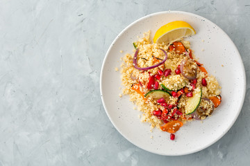 Vegetarian healthy couscous with roasted vegetables on grey background, top view, horizontal, copyspace