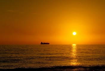 Fototapeta na wymiar Nave mercantile in viaggio nel mare durante il tramonto 