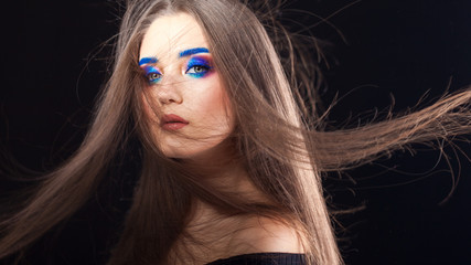 Fototapeta premium Attractive brunette with bright stylish make-up. Colored Smokey eyes and blue eyebrows.