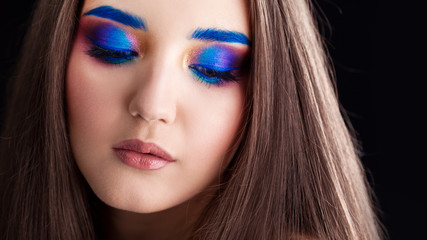 Naklejka premium Attractive brunette with bright stylish make-up. Colored Smokey eyes and blue eyebrows.