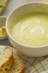 Homemade fresh healthy broccoli cream soup in white bowl with bread. side view. close up. vertical