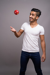 Young handsome Persian man against gray background