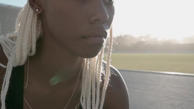 Close up of a confident female runner with blond braided hairstyle ready for the race on track. Sprinter looking focused ready to race on the track.