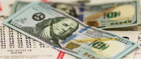 One hundred dollar bills over lottery tickets