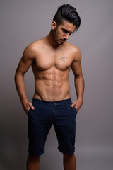 Young handsome Persian man shirtless against gray background