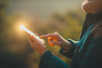 Cropped image of female hands holding mobile phone and browsing internet while hiking and having a...