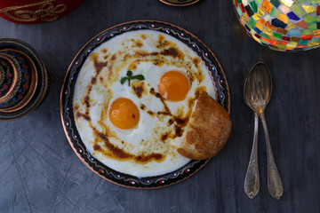 Cilbir, eggs in yogurt with spiced butter and herbs, served with bread and tea, turkish cuisine, copy space