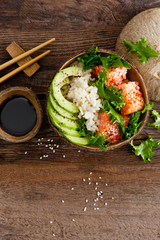 Hawaiian poke coconut bowl with grilled salmon fish, rice and avocado. Healthy food. Top view