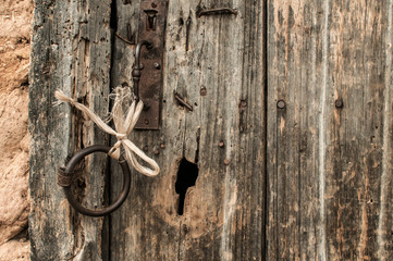Old aged weathered grunge wooden door detail with iron ring and handle closeup