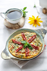 Traditional fritatta with dry tomatoes in a cast iron pan. White background, copy space