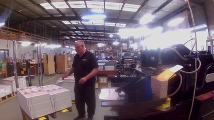 A printing machinist loading paper into his press, getting it ready to start printing.