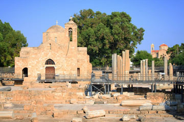 Obraz premium A large white church with a bell tower in ancient ruins in the midst of ancient columns on the island of Cyprus