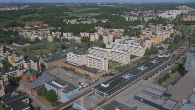 Wide view of Kista, the KTH campus and the transportation center. A bright blue bus on the road. Colorful modern buildings, landscape and the sea on the horizon. High angle view.