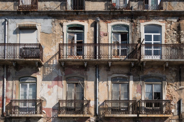 Dilapidated apartment building with balconies and flaking wall plaster